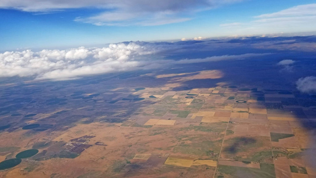 Green and brown fields with grey and white storm clouds above.