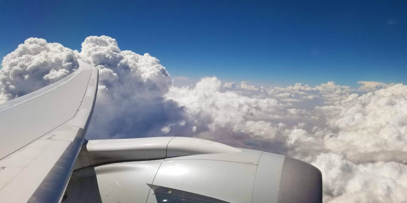 Looking out a plane window at puffy white clouds.